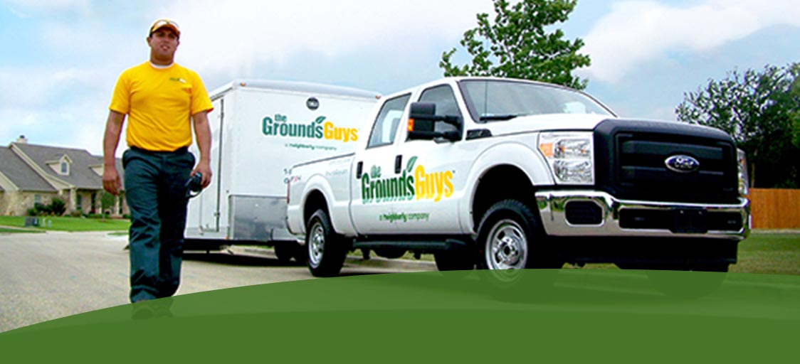 The Grounds Guys workers with a branded truck and trailer
