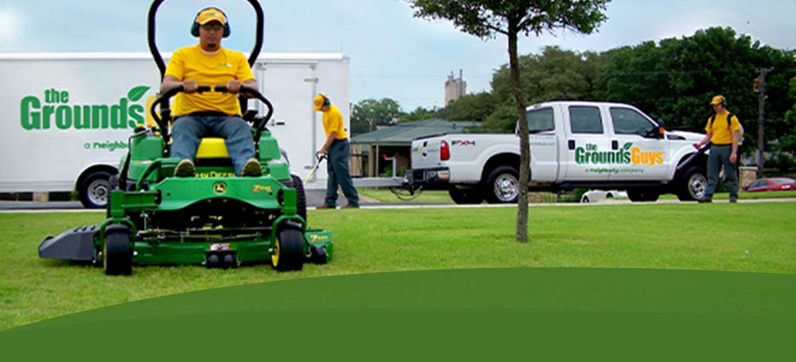 The Grounds Guys workers mowing and tending to a garden